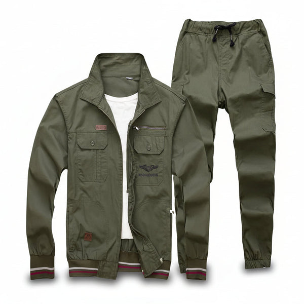 An olive green military-style jacket and matching cargo pants laid flat on a gray textured carpet background. The jacket is open to show a white undershirt, featuring flap pockets, a zippered chest pocket, and ribbed cuffs with red, white, and green stripes.